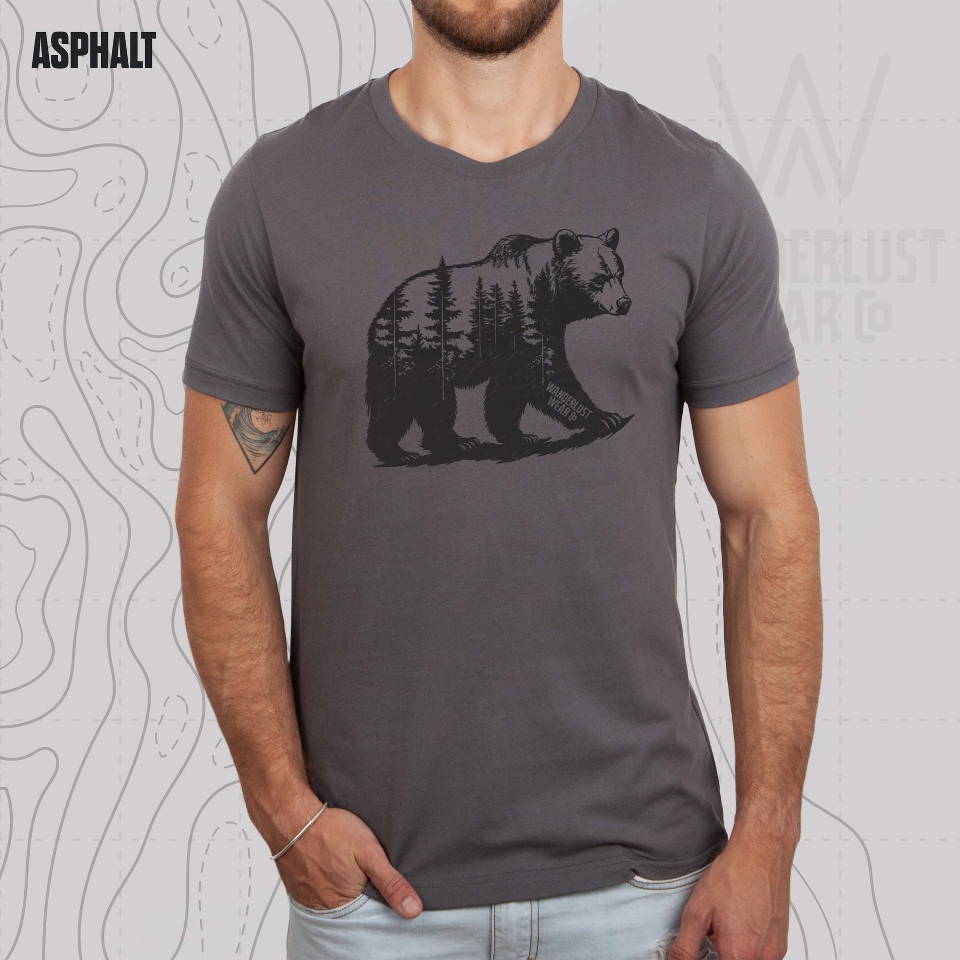 Model wearing Roam Wild Bear graphic tee in Asphalt, featuring hand-drawn bear silhouette with pine trees and Wanderlust Wear Co. branding