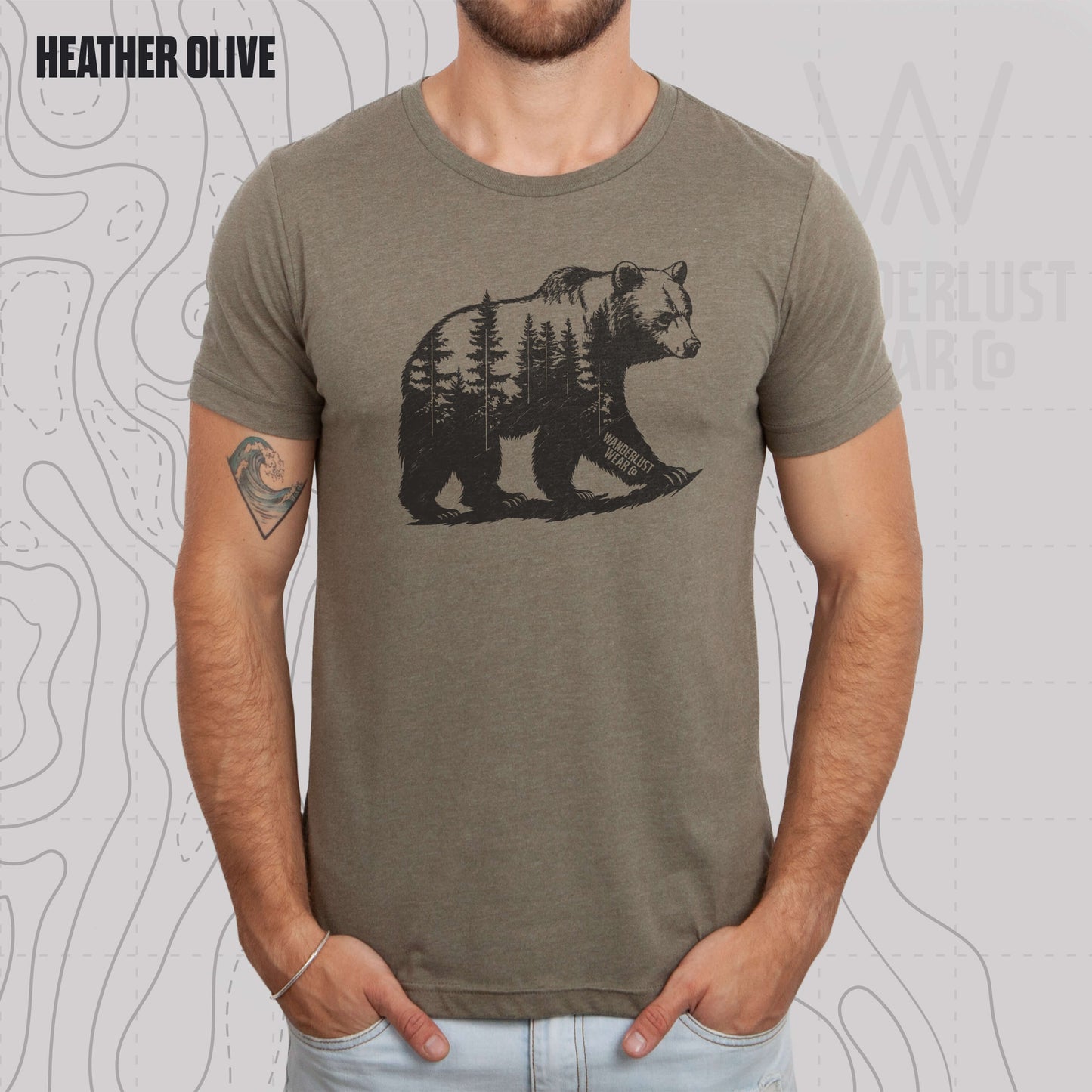 Model wearing Roam Wild Bear graphic tee in Heather Olive, featuring hand-drawn bear silhouette with pine trees and Wanderlust Wear Co. branding