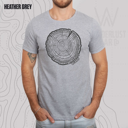 Model wearing Tree Rings Heritage graphic tee in Heather Grey, featuring hand-drawn tree trunk cross-section design by Wanderlust Wear Co.