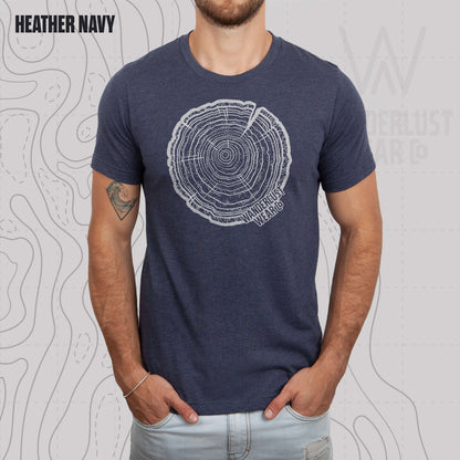 Model wearing Tree Rings Heritage graphic tee in Heather Navy, featuring hand-drawn tree trunk cross-section design by Wanderlust Wear Co.
