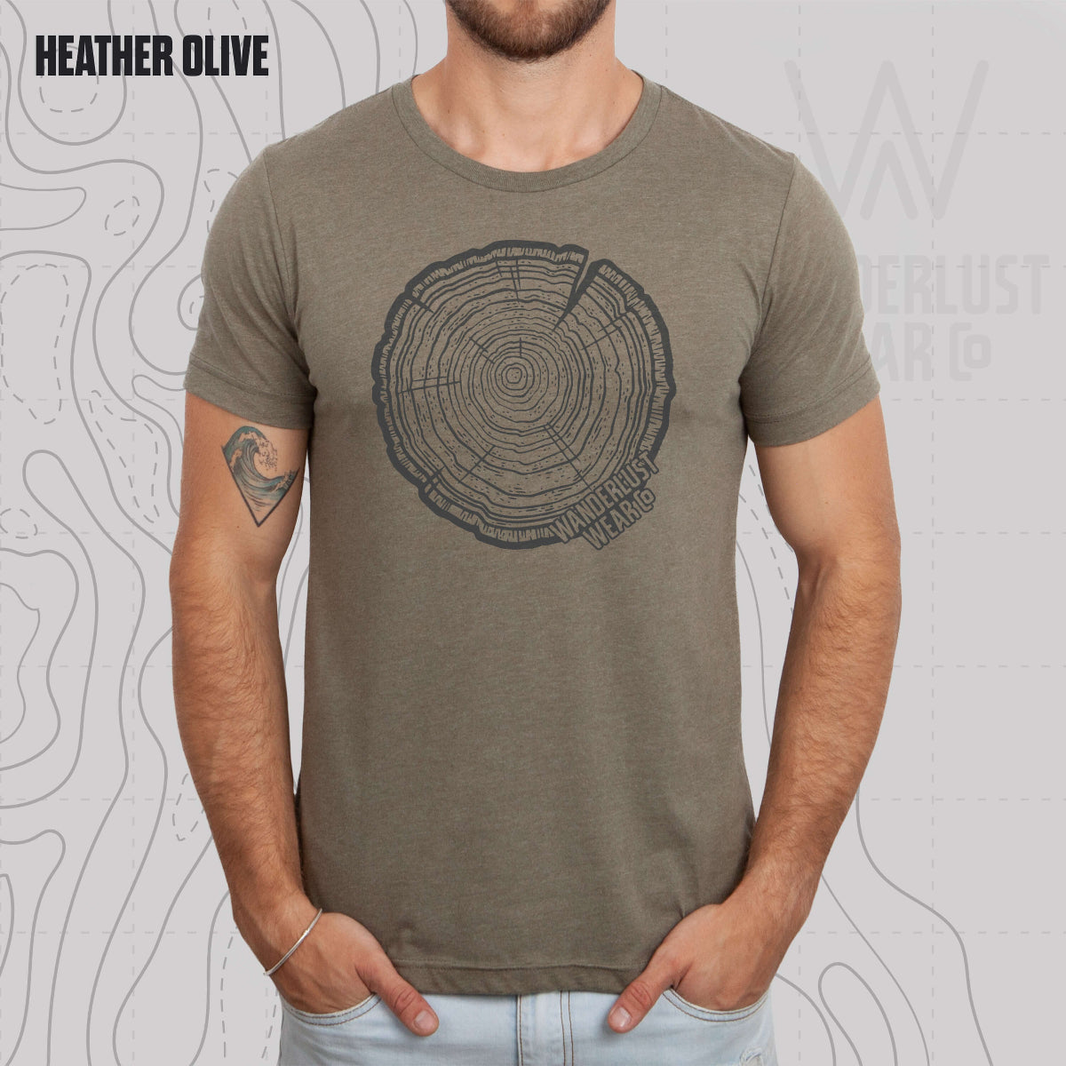 Model wearing Tree Rings Heritage graphic tee in Heather Olive, featuring hand-drawn tree trunk cross-section design by Wanderlust Wear Co.