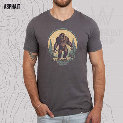Model wearing Wilderness Watcher graphic tee in Asphalt, featuring hand-drawn bear silhouette with pine trees and Wanderlust Wear Co. branding