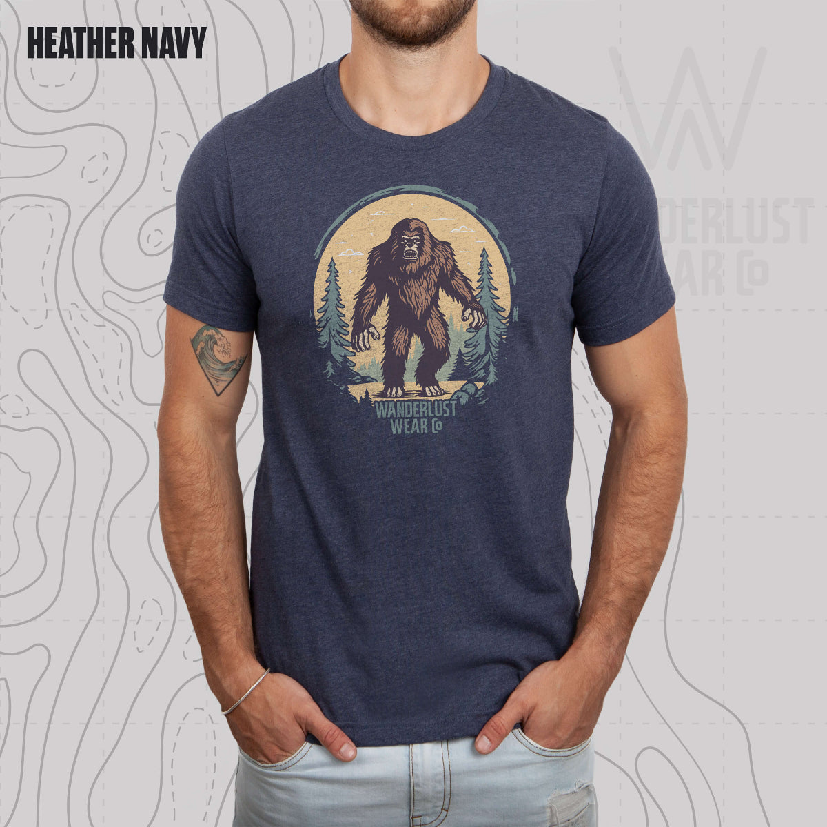 Model wearing Wilderness Watcher graphic tee in Heather Navy, featuring hand-drawn bear silhouette with pine trees and Wanderlust Wear Co. branding