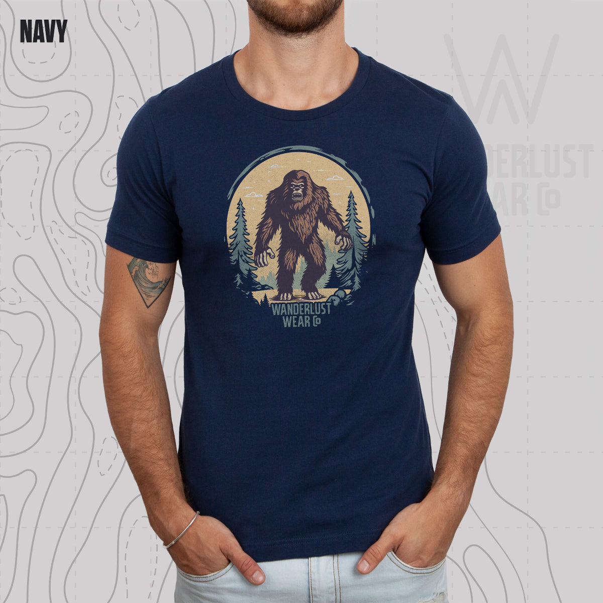 Model wearing Wilderness Watcher graphic tee in Navy, featuring hand-drawn bear silhouette with pine trees and Wanderlust Wear Co. branding
